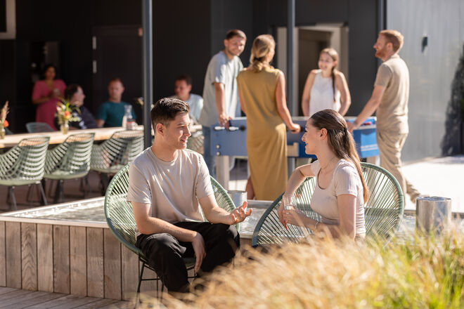 Menschen unterhalten sich und spielen Tischfußball in entspannter Atmosphäre, umgeben von natürlicher Schönheit. Perfekter Sommertag! Menschen unterhalten sich und spielen Tischfußball in entspannter Atmosphäre, umgeben von natürlicher Schönheit. Perfekter Sommertag!